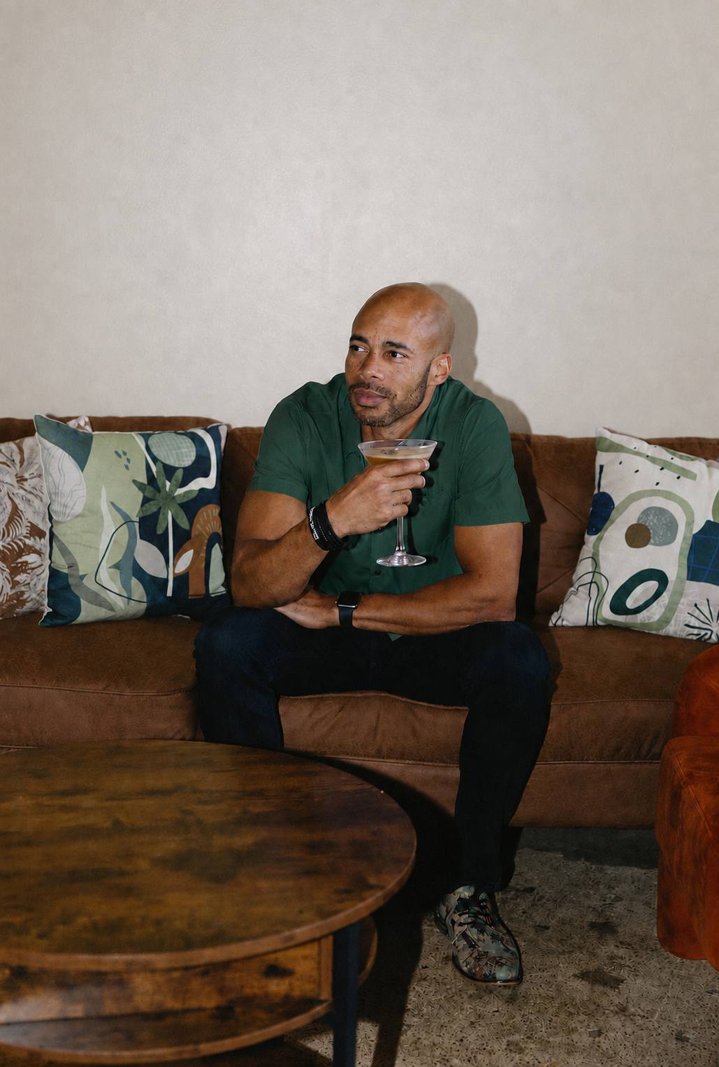 Guest seated on a couch with a stemmed drink, surrounded by patterned pillows and a coffee table