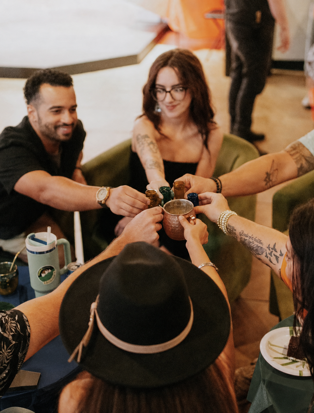 Overhead view of hands reaching toward a shared copper kava bowl with small cups